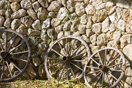 Old wooden wheels leaning up against stone wallの写真素材