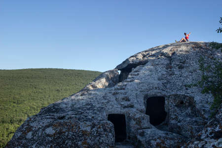 Cave city in the mountains. The girl is sitting on a rock.の写真素材