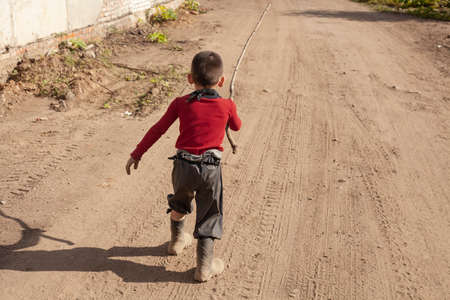 Naughty child running along a dusty road.の写真素材