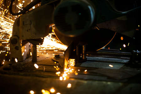 Metal cutting. Grinding steel. Work as a grinder. Sparks from friction. Men's work. Creating a design. The project in the workshop. Iron processing. Hand electric tool.の写真素材