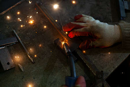 Metal welding. Sparks from electric heating. Work in the workshop. Creation of reliable fastening of materials. Fabrication of iron. The work of the master of metal.の写真素材