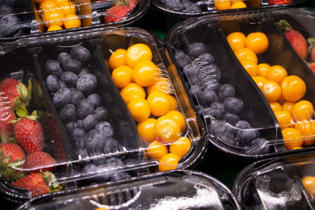 Fresh berries are packed in trays. Vitamin-rich fruits are packaged in boxes. A variety of fruits for sale in a store. Tasty berries.の写真素材