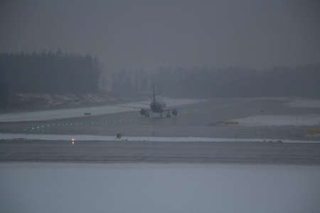 The plane lands on the runway in conditions of poor visibility. Cloudy weather at the airport. Passenger aircraft lands and landing landing gear. Landing aircraft in difficult conditions.の写真素材