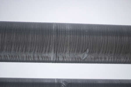 Pipes for hot and cold water. City communications. Heat pipe on the street. Elevated pipes conducting gas. Stainless steel. Industrial texture close-up. The object of industrial designation.の写真素材