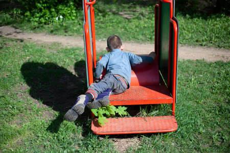Little boy plays in the playground. Entertainment without internet. Childhood child outdoors. A fun lesson for the cunning little boy. An interesting stay in the children's area.の写真素材
