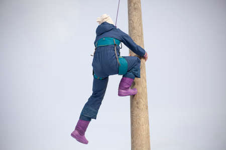 Children's mountain climbing. A girl climbs on a pole. A child with insurance climbs a tall pole. Fun in the park. Physical exercise to develop coordination of movement. A lesson in a physical training camp.の写真素材