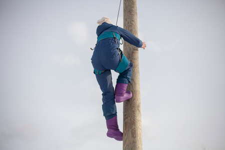 Children's mountain climbing. A girl climbs on a pole. A child with insurance climbs a tall pole. Fun in the park. Physical exercise to develop coordination of movement. A lesson in a physical training camp.の写真素材