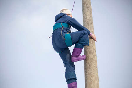 Children's mountain climbing. A girl climbs on a pole. A child with insurance climbs a tall pole. Fun in the park. Physical exercise to develop coordination of movement. A lesson in a physical training camp.の写真素材
