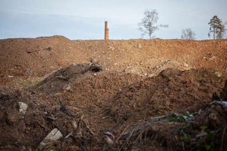 Bulldozer-blasted land. Development of the territory for construction. Earthworks. Trees destroyed with plowed land. Dug soil. A mound of sand for construction. Site preparation for the installation of the plant..の写真素材