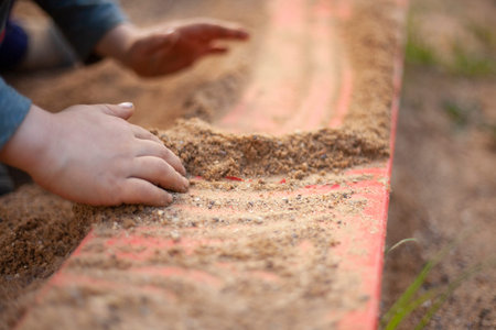 A child plays with the sand. Sand is pouring from the hands of a child. The development of fine...