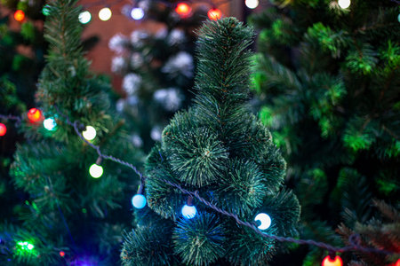 Garlands on a coniferous tree. Christmas tree decoration for the new year. Bright lights glow in the...
