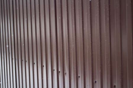 Metal fence around the building. The fence around the site. Wall painted in brown. Metal construction. Ribbed fence.の写真素材