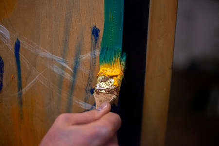 The artist paints with a brush on an easel. Oil paints. Abstract art. Colorful background. Disclosure of creative abilities. Hand holds a brush. Expression of self with paints. Development of drawing skills.の写真素材