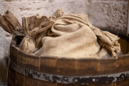 Canvas bag in a barrel. Things are in the barn. Country utensils. Beautiful antique background. The texture of the fabric.の写真素材
