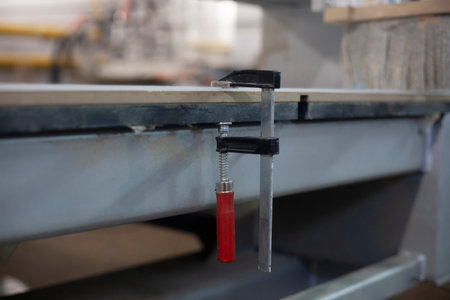 Materials pulled together with a clamp. Making a billboard in an advertising workshop. Tight fit of...