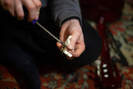 The musician tunes the guitar. Acoustic instrument. Do-it-yourself string instrument repair. Setting...