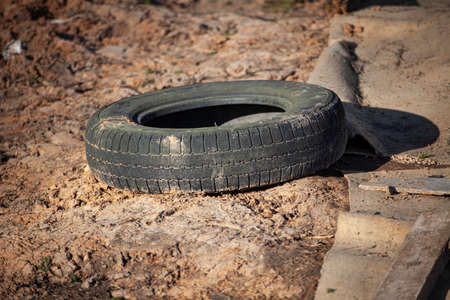The wheels are lying on the ground. Rubber tires thrown into the landfill. Environmental pollution. Disposal of wheels. Used and discarded items.の写真素材