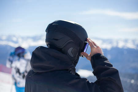 Snowboarder in a black helmet. Helmet to protect your head from shock. A man on a hillside getting ready for downhill.の写真素材