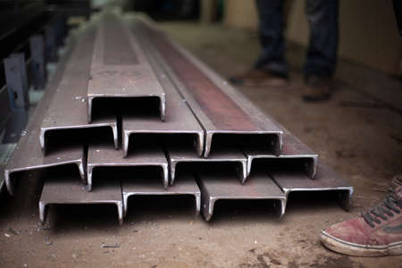 Steel beams in stock. Metal products in the workshop. The metal is prepared for loading. Industrial steelmaking.