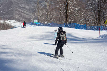 A skier rides on a snowy slope. Active rest in the winter. The athlete is preparing for the descent. Mountain ski resort. Outdoor activities on a winter vacation. The best time of the season. Man in a suit protecting from snow.の写真素材