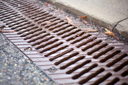 Stormwater to drain water after rain. Means for draining water on the road. Streams flow into a hole in the asphalt. Mesh metal tool for the flow of water.の写真素材