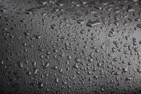 Drops of water on a black panel. Candensate on a black surface. The texture of the drops. Background from homogeneous elements in the form of water.の写真素材