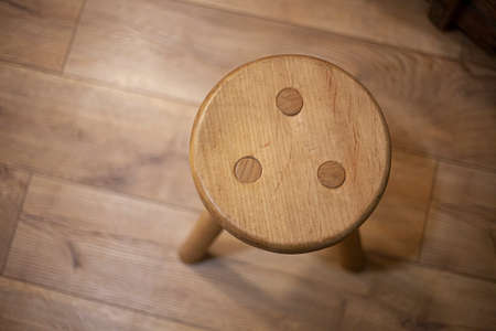 Seat made of wood. Furniture for home. Stool in the old style. Vintage object. Shades of yellow in the interior. A chair made by the hands of a craftsman.の写真素材