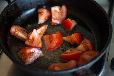 Tomatoes are fried in a pan in oil. Cooking dinner at home. Tomato juice appears during cooking. Food in the family. Cases in the kitchen. Tasty recipe.の写真素材