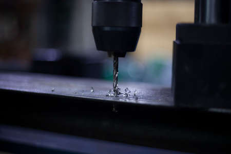 A modern drill for creating holes in metal. Work as a drill in the workshop. Replacing the drill after use. Preparing for work. Background is my hobby. Drill holes in a metal beam.の写真素材