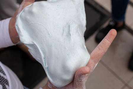 The child wrinkles slime in his hands. Sticky substance. Products made from flour with pulling properties. Two hands wrinkle a light soft thing.の写真素材