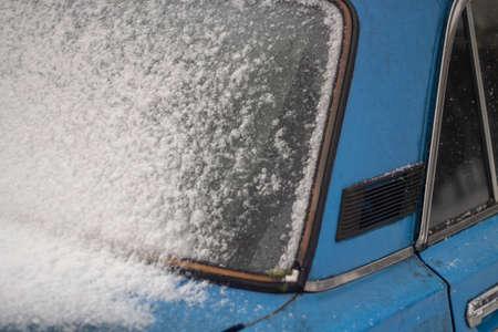 The car in the parking lot is covered in snow. Transport in the parking lot in winter. Frozen car windows.の写真素材