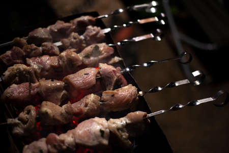 The meat is fried over an open fire. Skewers set on skewers are cooked on a mongal. National cuisine of the Caucasian peoples. Delicious meat gives juice from high temperature. Cooking at night on the street.の写真素材
