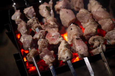 The meat is fried over an open fire. Skewers set on skewers are cooked on a mongal. National cuisine of the Caucasian peoples. Delicious meat gives juice from high temperature. Cooking at night on the street.の写真素材