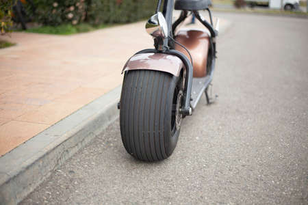 E-bike with wide wheels for city driving. Moped in retro style. Parked electric vehicles. Way to get around the street. Scooter rental at the resort.の写真素材