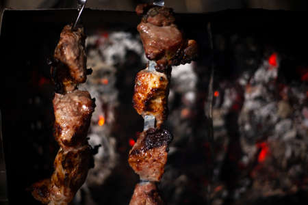 The meat is fried over an open fire. Skewers set on skewers are cooked on a mongal. National cuisine of the Caucasian peoples. Delicious meat gives juice from high temperature. Cooking at night on the street.の写真素材
