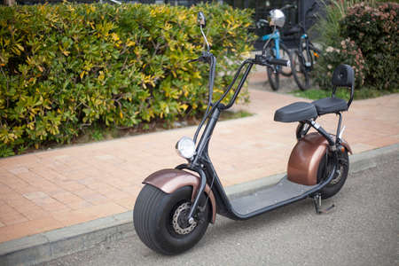 E-bike with wide wheels for city driving. Moped in retro style. Parked electric vehicles. Way to get around the street. Scooter rental at the resort.の写真素材