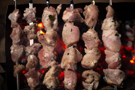 The meat is fried over an open fire. Skewers set on skewers are cooked on a mongal. National cuisine of the Caucasian peoples. Delicious meat gives juice from high temperature. Cooking at night on the street.の写真素材