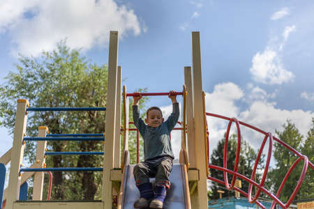 Little boy plays in the playground. Entertainment without internet. Childhood child outdoors. A fun lesson for the cunning little boy. An interesting stay in the children's area.の写真素材