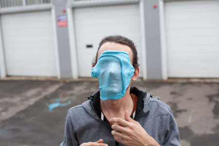 A guy with mucus on his face portrays a monster. The young man is trying to scare. The man made a mask from a viscous substance and applied it to his head.の写真素材