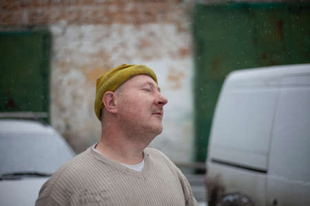 Portrait of a middle-aged man after a hard working day. The face of the master of metal. The guy in the yellow hat. Tired facial expression. Shooting indoors. Man tired of labor. A terrible hangover after alcohol.の写真素材