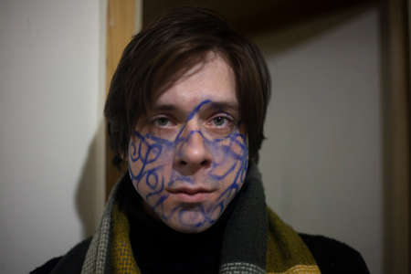 A guy with drawings on his face. King of the party. The spiritual seeker is crazy. A young man with a picture on his face. Pottert business man. A subject confused with thoughts fights depression.の写真素材