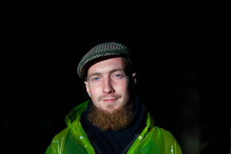 A guy with a long beard and an old-fashioned cap. Natural light when shooting. A lit face against a...