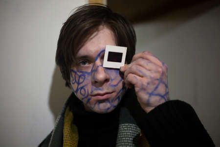 A guy with drawings on his face. King of the party. The spiritual seeker is crazy. A young man with a picture on his face. Pottert business man. A subject confused with thoughts fights depression.の写真素材