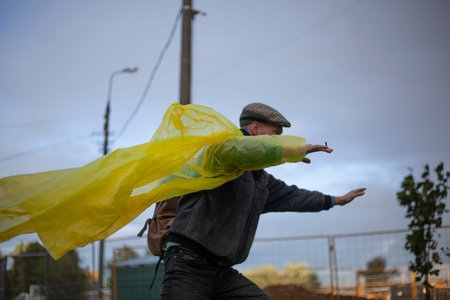 The guy in the yellow rain jacket on the street. A man on a cloudy day rejoices in the rain....