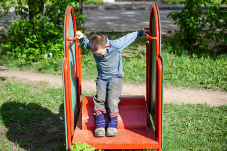 Little boy plays in the playground. Entertainment without internet. Childhood child outdoors. A fun lesson for the cunning little boy. An interesting stay in the children's area.の写真素材