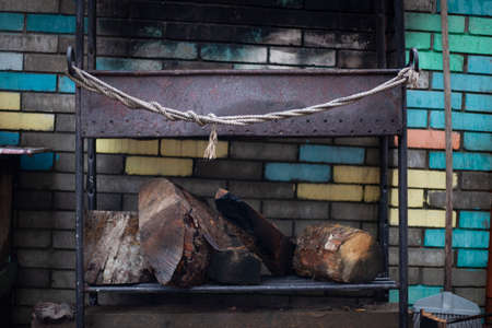Barbecue for frying meat is in the yard. Rope on the iron structure. Place for a fire. Twisted metal elements in the decoration of the old brazier.の写真素材