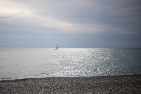 Sea shore. Sailing boat far into the sea. Girls on the shore. Seascape. Calm wave. Rocky embankment....