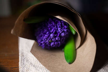 Bouquet of flowers on the table. Purple flower in craft paper. A gift for your beloved. A sign of attention for a woman. Beautiful flower background.の写真素材