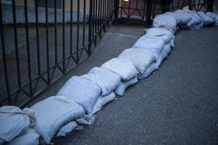 Sandbags to protect against flooding by water from the mountains. Little dam on the street. Bags lie in a row along the carriageway. The entrance to the hospital is blocked.の写真素材