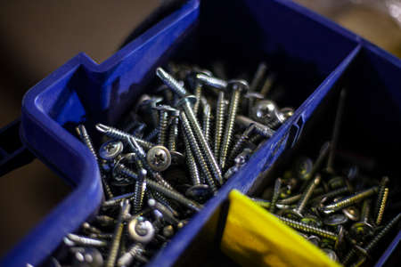 The screws are in the tool box. Accessories for fastening parts. Storage of small items in a blue box. The order in the workshop.の写真素材